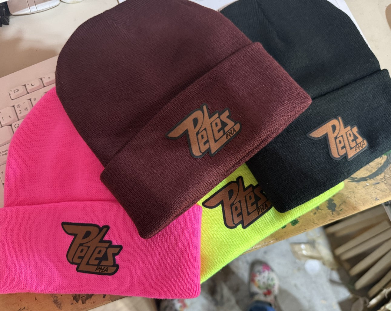 Four beanies in different colors with 'Petes' logo on a surface.
